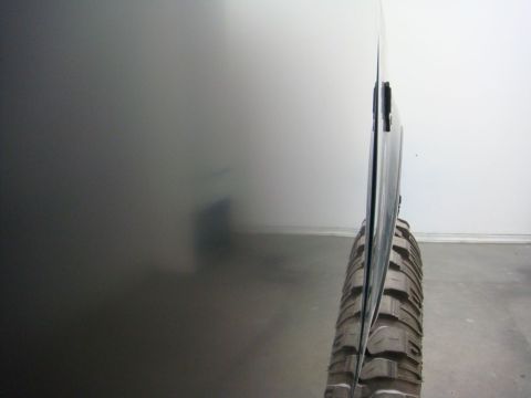 1996 Ford Bronco - A close-up shot focuses on the side of a vehicle's door and a tire, with a blurred background.