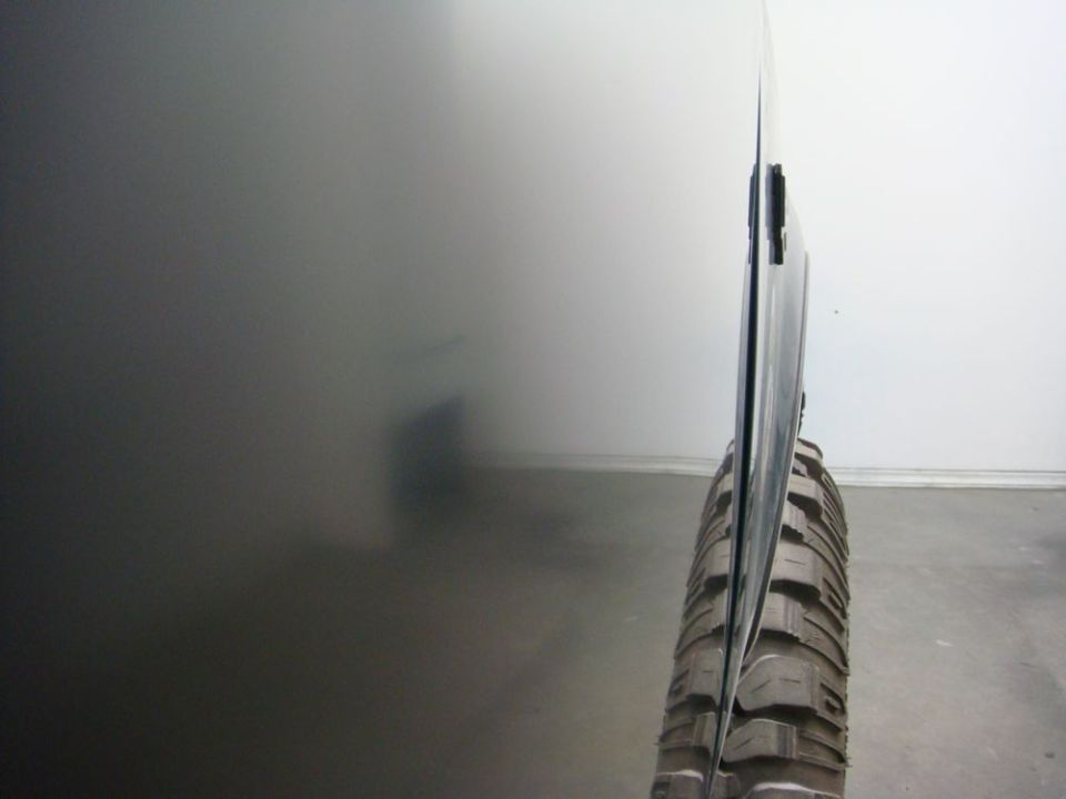 Side view of a vehicle door and a large off-road tire