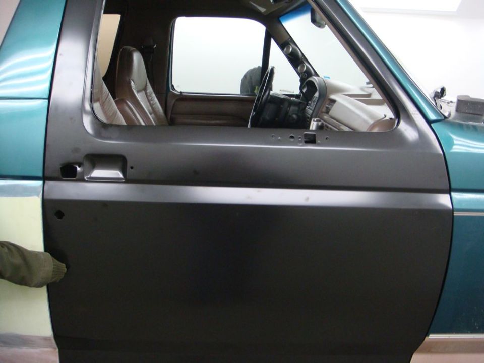 Driver's side door panel of a 1990s Ford Bronco, showing the interior and steering wheel