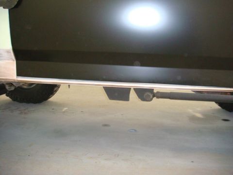 1996 Ford Bronco - Close-up view of the side of a vehicle, focusing on the lower body panel and visible suspension parts.