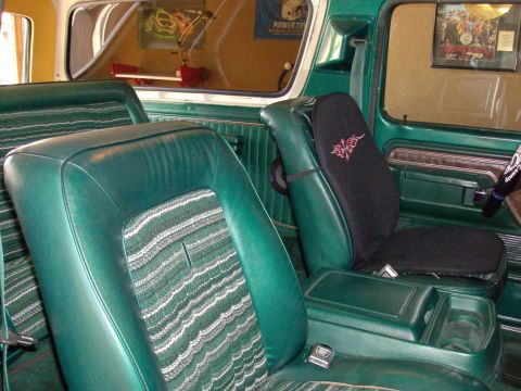 1978 Ford Bronco - The interior of a 1978 Ford Bronco features green vinyl seats with striped fabric inserts and a functional center console.