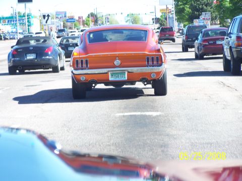1972 Ford Ranchero - Rear view of an orange fastback car driving in traffic, license plate reads MY68TOY.