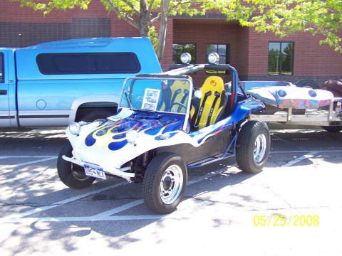 1972 Ford Ranchero - A custom dune buggy with flame decals is parked next to a blue pickup truck, with another vehicle body on a trailer behind it.