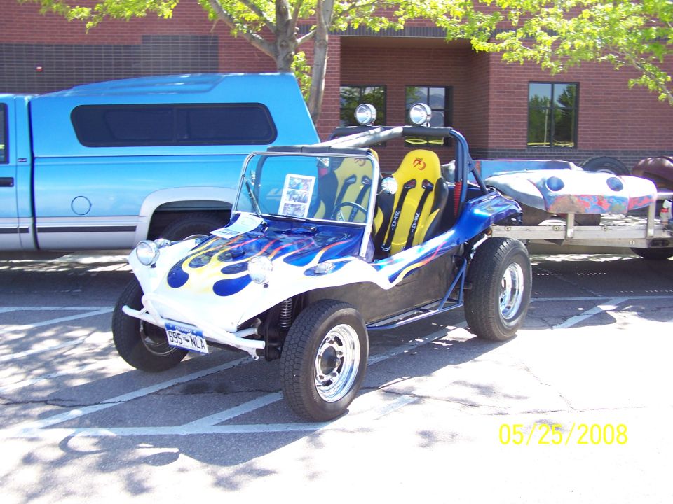 Dune buggy with blue and white flames, yellow racing seats, and a trailer carrying another vehicle body