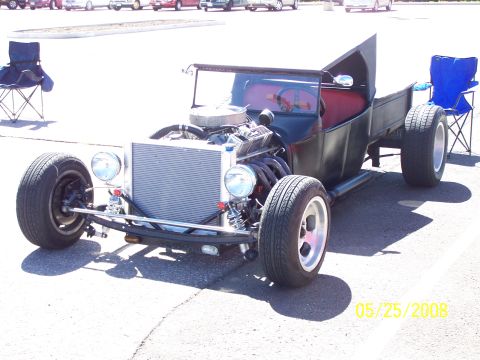 1972 Ford Ranchero - A custom hot rod pickup truck with a prominent engine and a red interior sits on display at an outdoor car show.