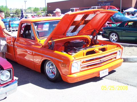 1972 Ford Ranchero - Orange pickup truck at car show, hood open. Another vehicle visible in the background.