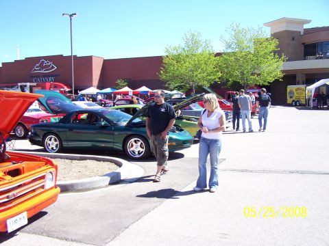 1972 Ford Ranchero - A car show is taking place in a parking lot with several vehicles and people present.
