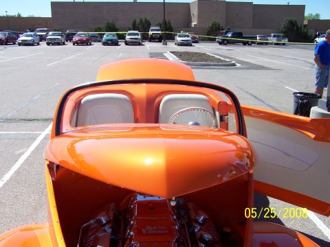 1972 Ford Ranchero - A custom orange hot rod is displayed at an outdoor car show with other vehicles present.