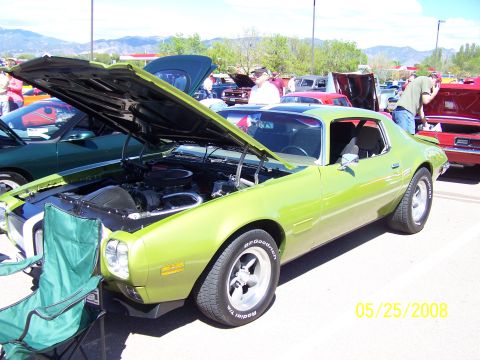 1972 Ford Ranchero - A lime green muscle car is displayed with its hood open at a car show, with other vehicles and spectators in the background.