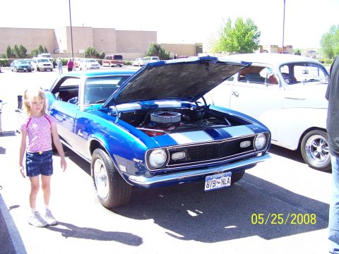 1972 Ford Ranchero - Blue 1969 Chevrolet Camaro with racing stripes and open hood at a car show.