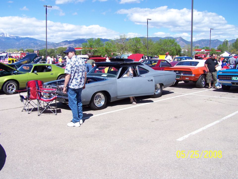 Gray coupe with open door and hood, custom wheels, parked at car show