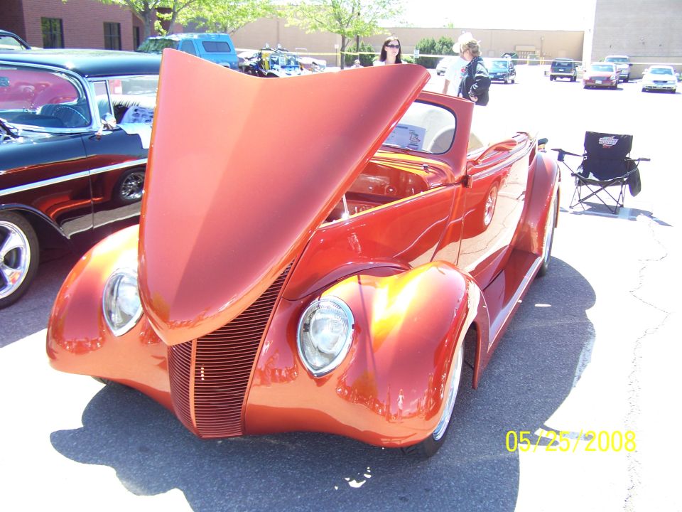Orange custom hot rod with hood open, viewed from the front