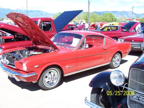 1972 Ford Ranchero - A red 1965 Ford Mustang is displayed at a car show with other vehicles.