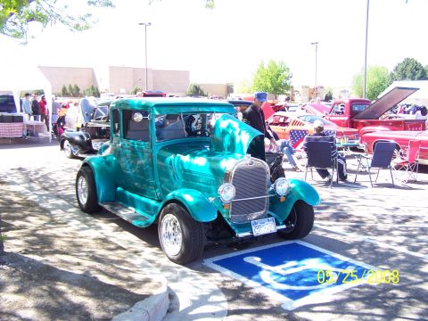 1972 Ford Ranchero - A teal hot rod coupe is displayed at an outdoor car show with other vehicles and people around.