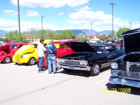 1972 Ford Ranchero - Several classic cars are parked in a lot under a partly cloudy sky. One black convertible is in the foreground.