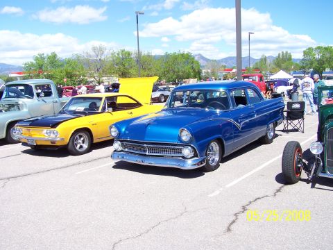 1972 Ford Ranchero - A blue 1955 Ford Fairlane sedan is displayed at a car show with other vehicles.