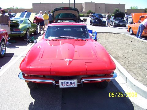 1972 Ford Ranchero - A red 1963 Chevrolet Corvette Sting Ray is displayed at a car show, with other vehicles visible in the background.