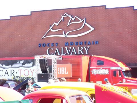 1972 Ford Ranchero - A car show event is underway with classic vehicles and a semi-truck parked outside a building.