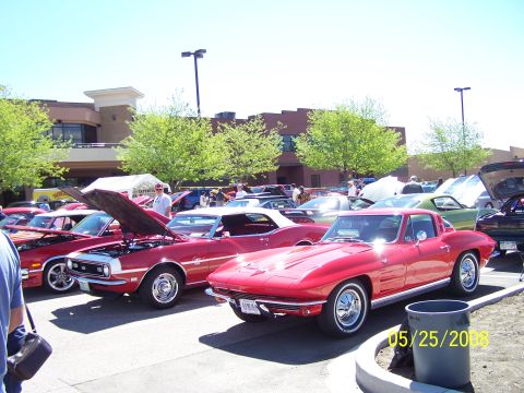 1972 Ford Ranchero - A red 1963 Chevrolet Corvette Sting Ray coupe is displayed at an outdoor car show with other vehicles.
