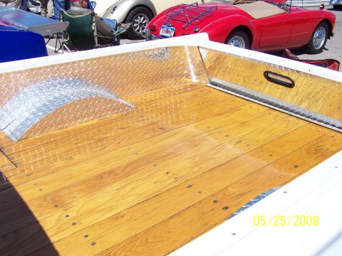1972 Ford Ranchero - The bed of a pickup truck features a polished wooden floor and diamond plate accents, with other vehicles parked behind.