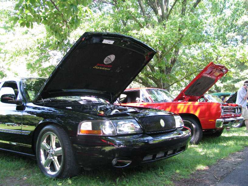 Black Mercury Marauder with hood open, parked next to a red classic car.