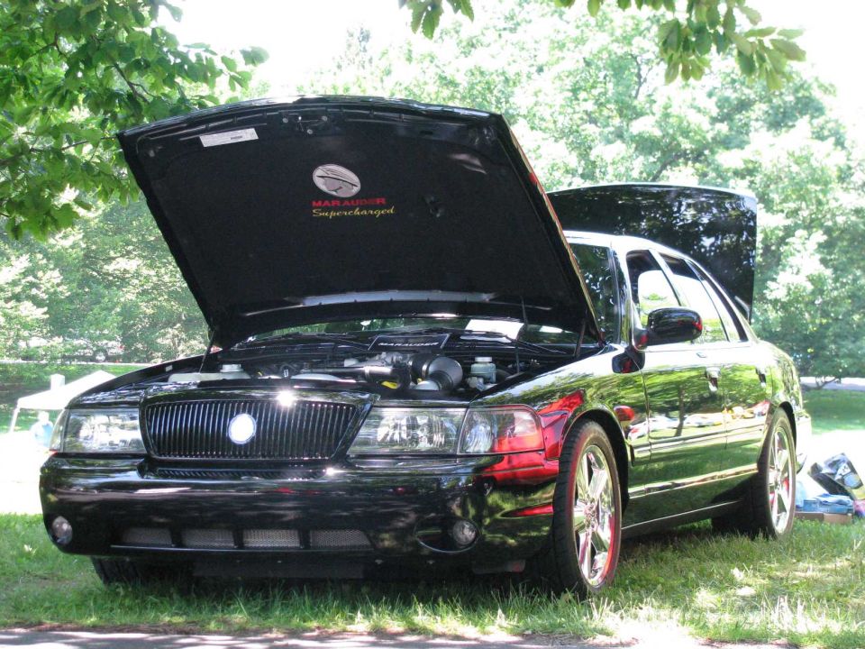 Black 2003 Mercury Marauder with hood open, showing engine and supercharged emblem.