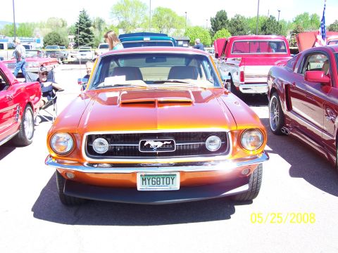 1972 Ford Ranchero - A front view of an orange Ford Mustang convertible parked among other vehicles.
