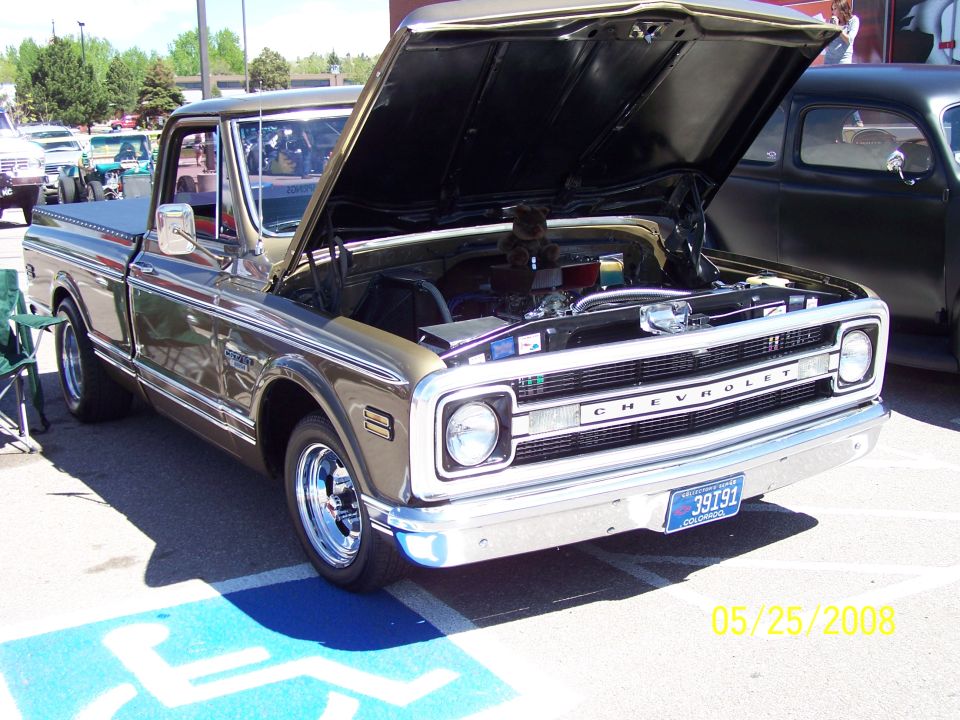 Green 1969-70 Chevrolet C10 pickup with hood open showing engine bay
