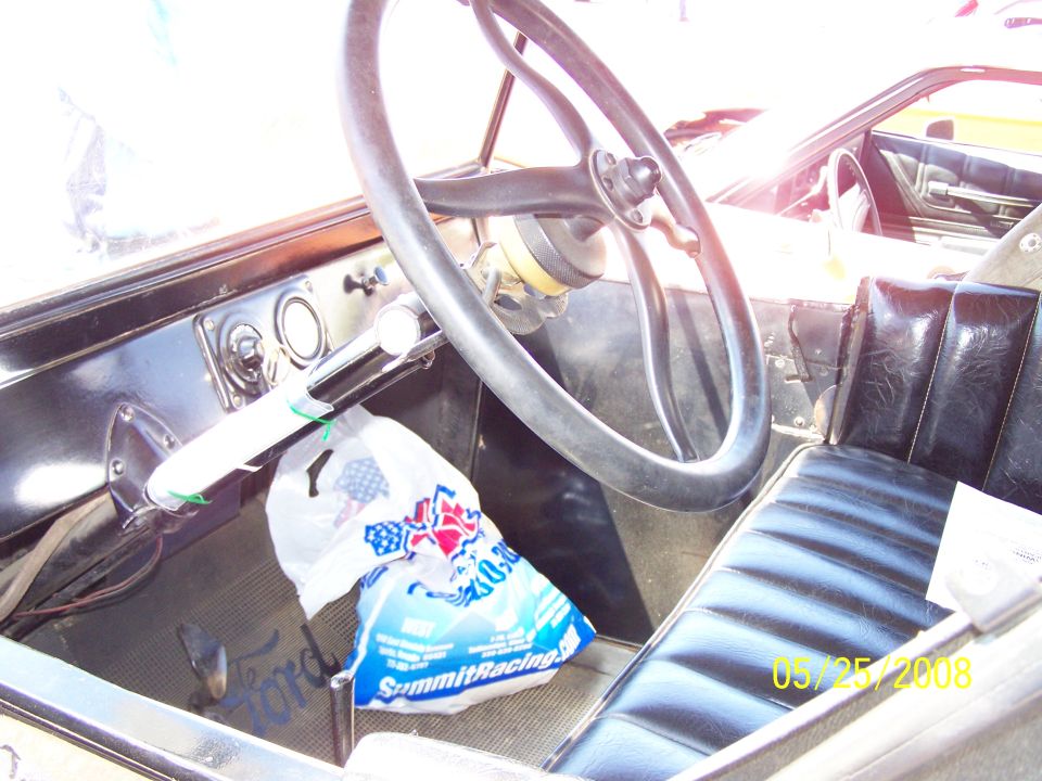 Interior of a stripped hot rod with black steering wheel and bench seat