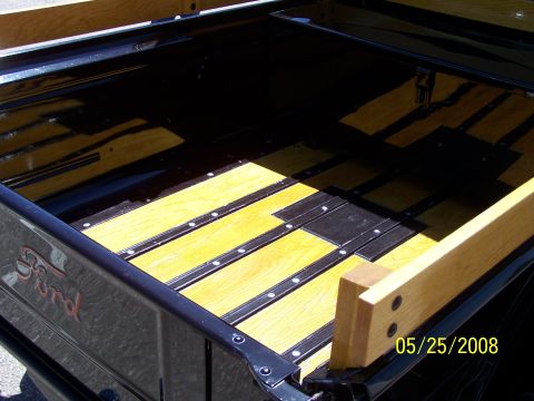 1972 Ford Ranchero - The interior of a Ford truck bed displays a custom wood and metal floor with the iconic Ford script visible on the side.