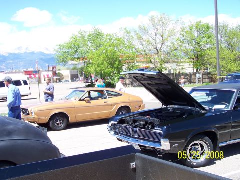 1972 Ford Ranchero - Two vintage cars are displayed at an outdoor event, with mountains in the background.