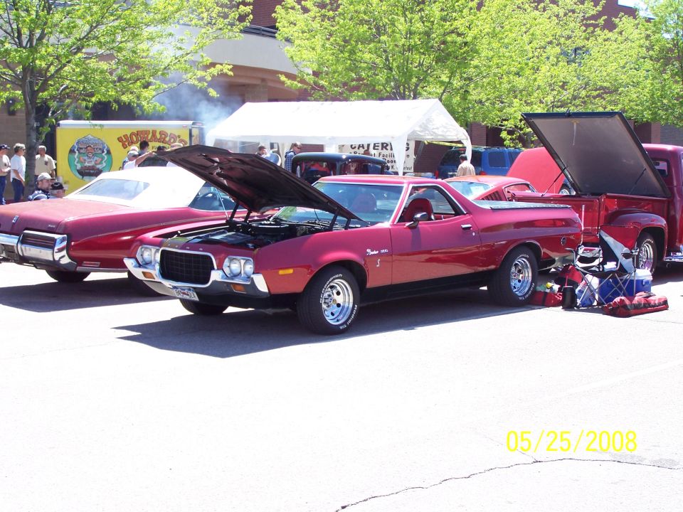 red coupe utility with hood open, parked next to a red pickup truck with its tailgate down