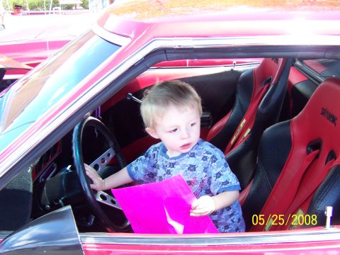 1972 Ford Ranchero - A young child is seated in the driver's seat of a car with red racing seats.