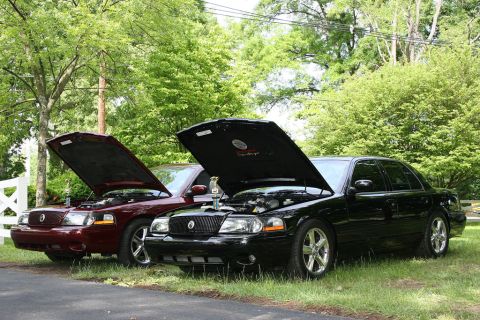2003 Mercury Marauder - Two 2003 Mercury Marauders are parked outdoors with their hoods raised, revealing their engines.