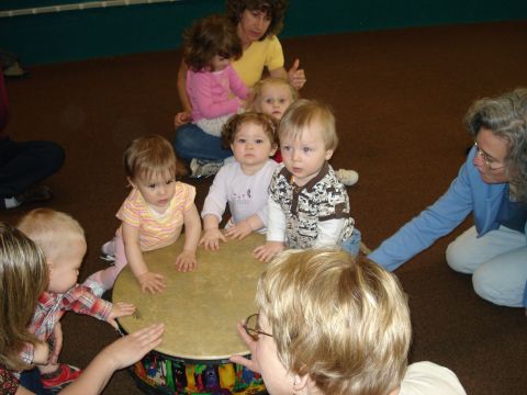 2000 Ford Crown Victoria - A group of young children and adults are interacting around a large drum in a room.