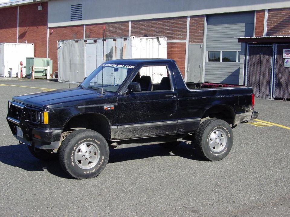 Black lifted topless Chevy S-10 Blazer 4x4 on off-road tires in front of a brick building