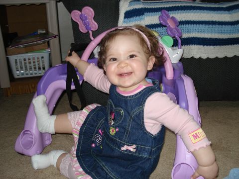2000 Ford Crown Victoria - A smiling baby girl in a denim jumper and pink shirt is playing with a colorful toy structure.