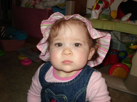 2000 Ford Crown Victoria - Baby wearing a sun hat and overalls sits in a room with toys.