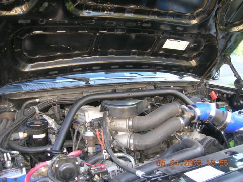 1996 Ford Bronco - Close-up view of the engine bay, highlighting the intake system with blue intercooler piping and twin turbo setup.
