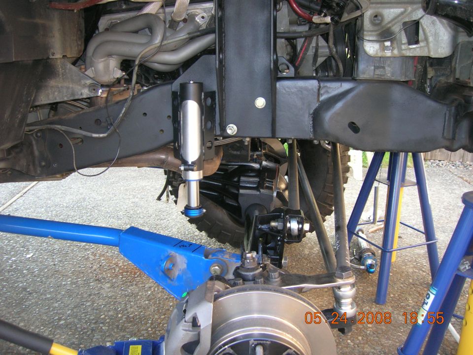 Close-up of vehicle front suspension with shock absorber, steering linkage, and brake rotor