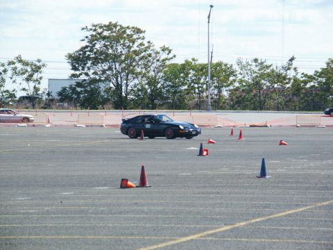 2001 Mercury Grand Marquis - A dark sports car navigates a course marked by traffic cones on a paved lot.