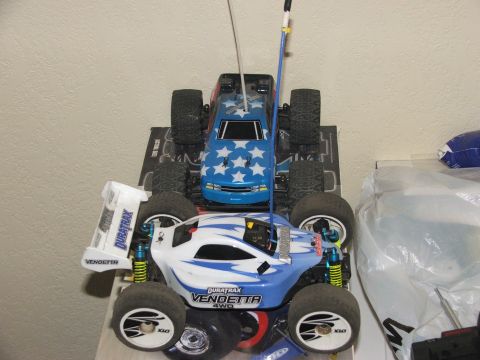 2000 Nissan Frontier - Two Duratrax RC monster trucks are displayed, one with a star pattern and the other with flame graphics.