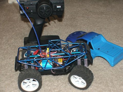 2000 Nissan Frontier - A remote control monster truck with its body removed sits next to a separate blue truck body and controller.