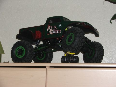 2000 Nissan Frontier - Two monster truck toys displayed on a shelf, one large green and one small yellow.