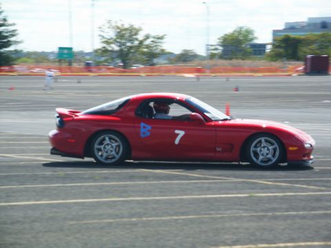 2001 Mercury Grand Marquis - A red sports car with racing numbers drives on a track during an event.