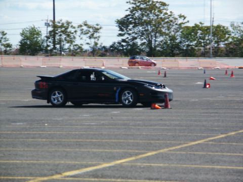2001 Mercury Grand Marquis - A black sports car navigates a course marked by traffic cones on a paved lot.
