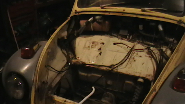 Yellow Volkswagen Beetle engine bay with exposed wiring and components