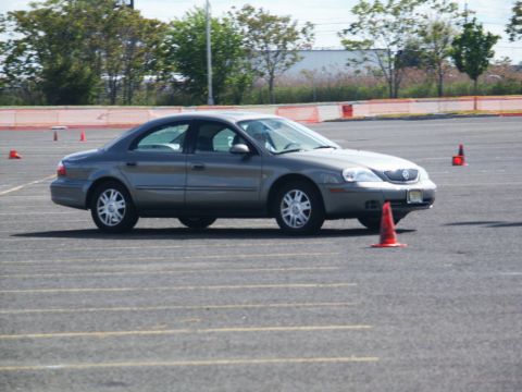 2001 Mercury Grand Marquis - A gray 2001 Mercury Grand Marquis navigates a course marked by orange cones on a paved lot.