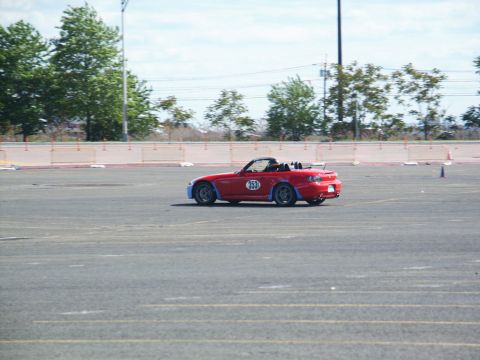 2001 Mercury Grand Marquis - A red convertible sports car is seen on a paved lot, possibly during a timed event.