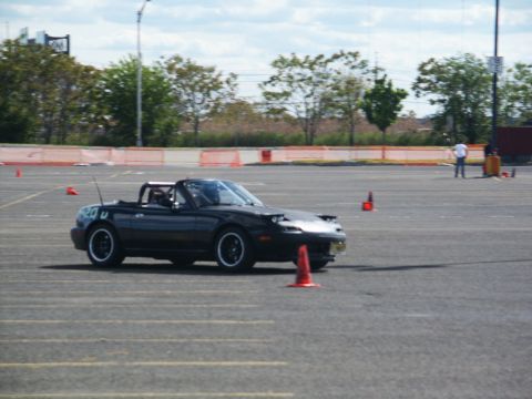 2001 Mercury Grand Marquis - A black convertible sports car is seen on a paved lot with orange cones, likely during a timed event.